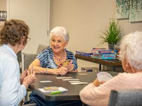 Three elderly women playing a card game at a table.