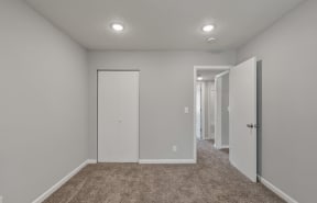 a bedroom with a carpeted floor and a door to a closet