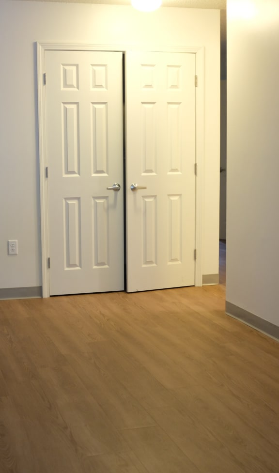 an empty living room with two doors and a wood floor