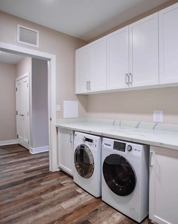 a washer and dryer in a laundry room with white cabinets