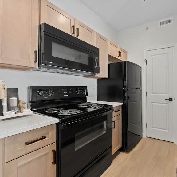 A kitchen with black appliances and wooden cabinets.