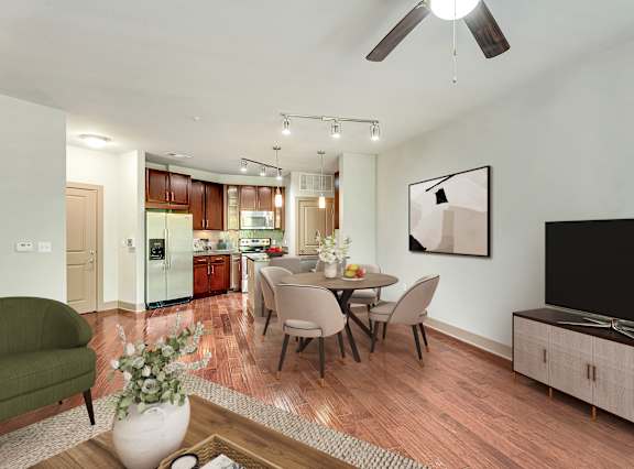 A modern living room with a green armchair, a dining table set for four, and a television on the wall.