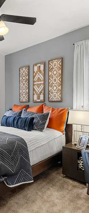 A bedroom with a bed, a couch, and a ceiling fan.