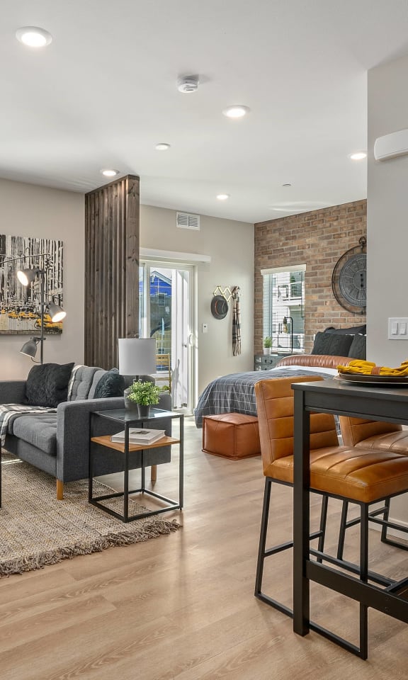 Open floorplan with light gray walls, brick accent wall, and partial dividers.