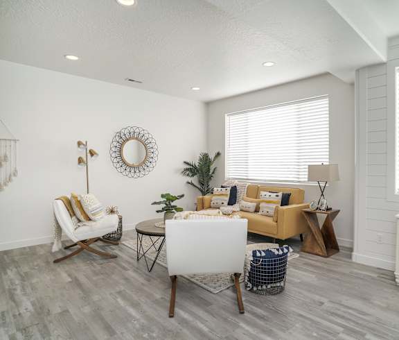 A living room with a white sofa, a white chair, a white coffee table, a white side table, and a white dresser.
