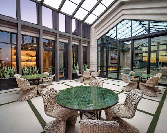 A glass-roofed room with a green table and chairs.