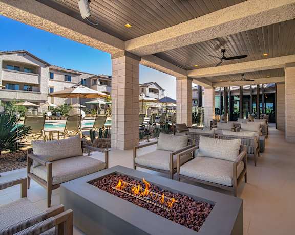 A patio with a fire pit and chairs.