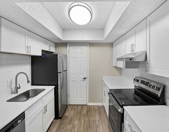 A small, white kitchen with a black fridge and stove.