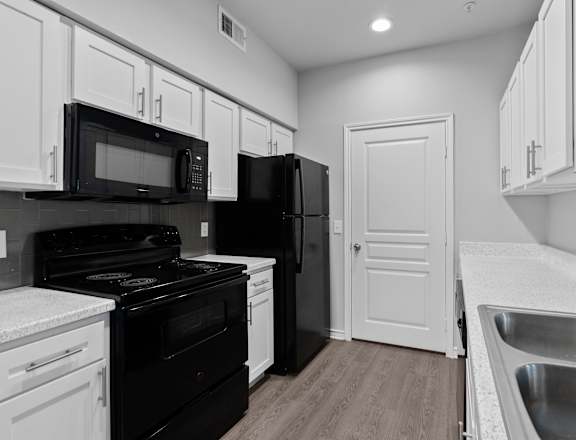 A kitchen with black appliances and white cabinets.