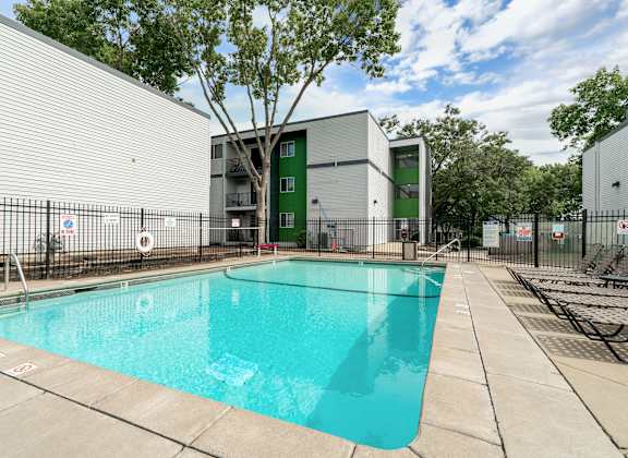 A swimming pool in front of a building with a green door.