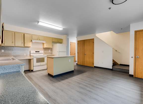 A kitchen with a refrigerator, oven, and sink.