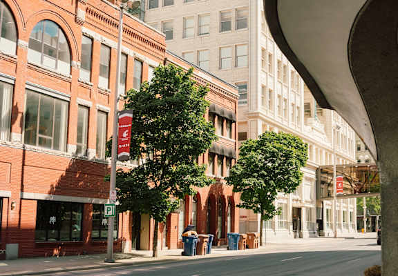 A street view of a city with buildings, trees, and a no parking sign.