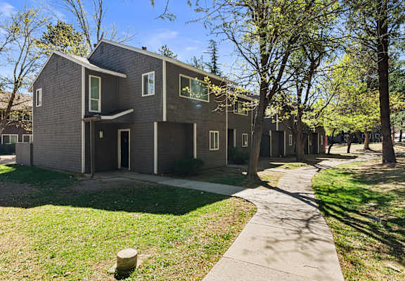 A modern house with a grey facade and a green lawn in front.