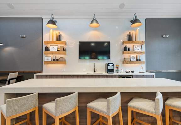 a kitchen with a counter and chairs and a tv on the wall