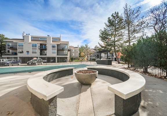 A circular concrete bench with a planter in the middle is surrounded by a concrete walkway.