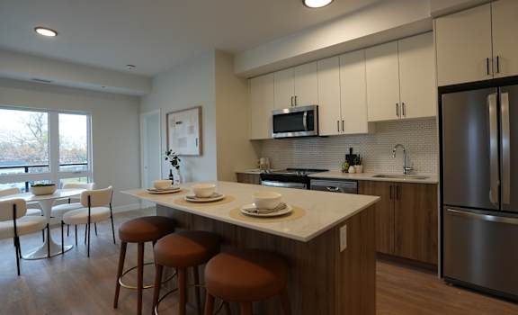 A kitchen with a white counter top and brown bar stools.