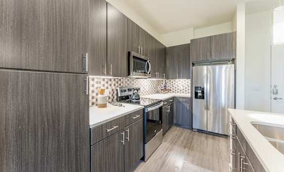 Updated Kitchen With Black Appliances and wooden cabinets at Residences at 3000 Bardin Road, Grand Prairie, TX, Texas