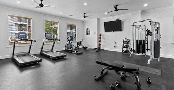 A spacious home gym with treadmills, exercise equipment, and a flat screen TV.
