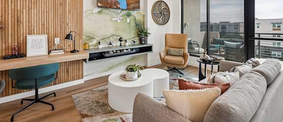 A modern living room with a green chair and a large painting on the wall.