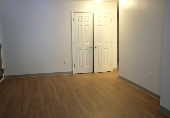 an empty living room with two doors and a wood floor