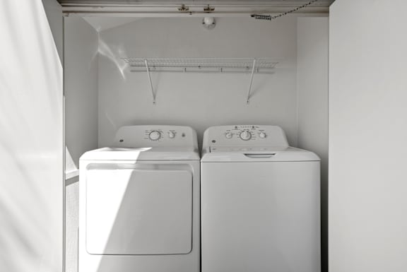 an empty laundry room with two washes and a dryer