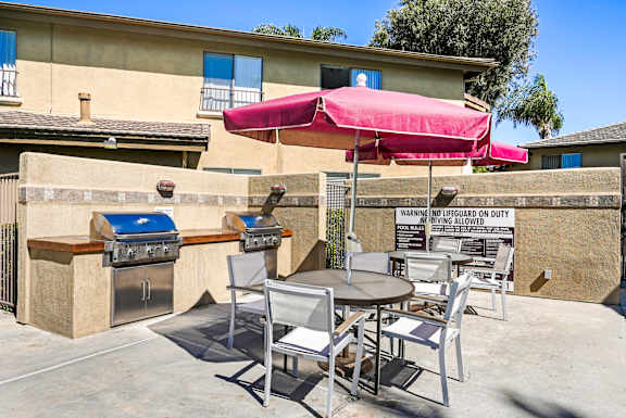 a patio with tables and chairs and a barbecue grill