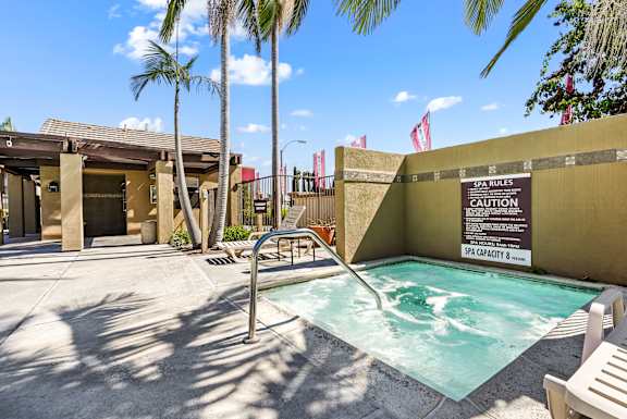 a hot tub in a pool in front of a building with palm trees