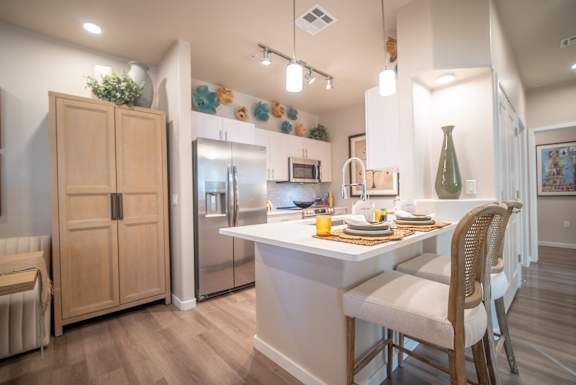 A kitchen with a white island and wooden chairs.