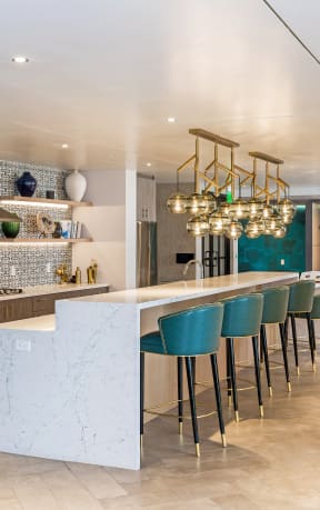 a kitchen with a long counter and a long bar with blue chairs