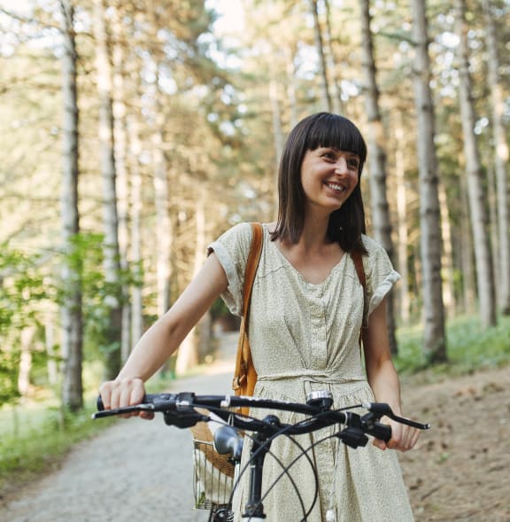 a woman riding a bike down a trail in the woods at The Woods, Kanata, Ottawa, Ontario