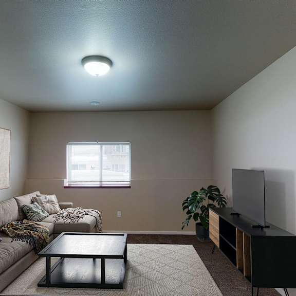 A living room with a grey couch, a black coffee table, and a flat screen TV.