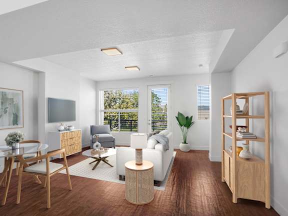 A modern living room with a glass table and chairs, a sofa, a TV, and a bookshelf.