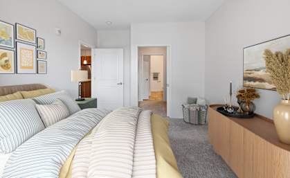 a bedroom with a bed and a dresser and a hallway to a bathroom