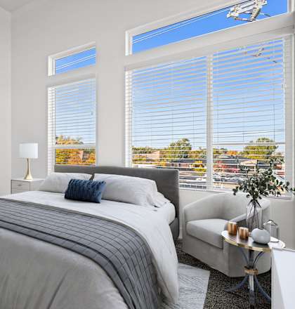a bedroom with a bed and three large windows