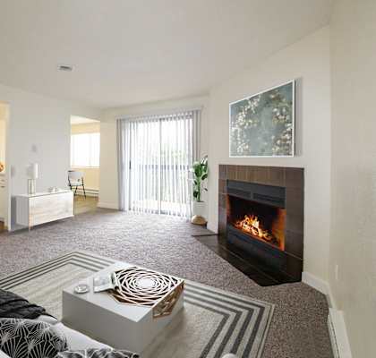 a living room with a fireplace and a kitchen in the background
