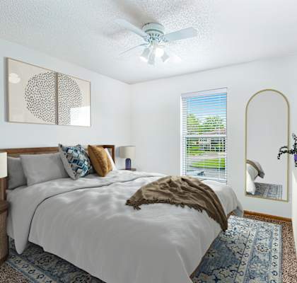 A bedroom with a bed, nightstand, and a window with a view of a green landscape.