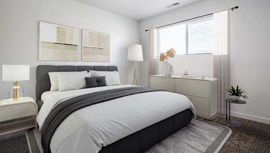A bedroom with a large bed and a nightstand with a lamp.