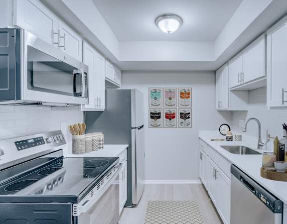 A modern kitchen with white cabinets and stainless steel appliances.