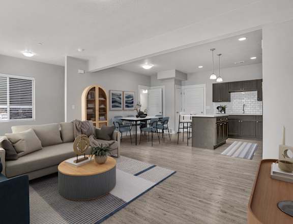A modern living room with a grey sofa, a wooden coffee table, and a dining area in the background.