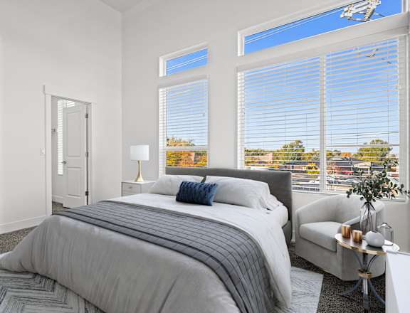 a bedroom with a bed and three large windows