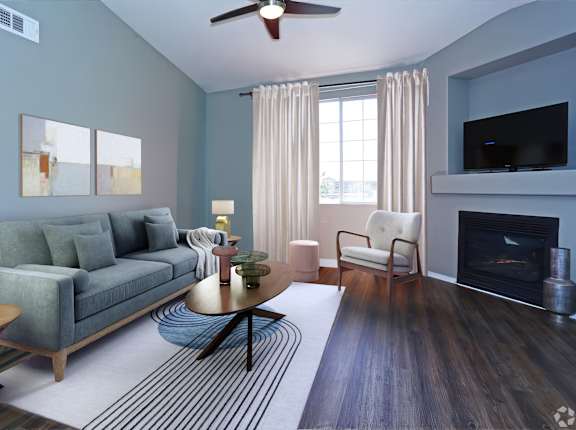 A living room with a grey couch, a fireplace, and a ceiling fan.