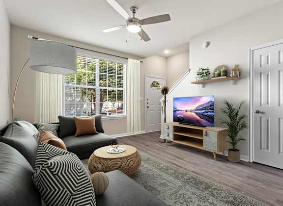 A living room with a grey couch and a television on a wooden stand.