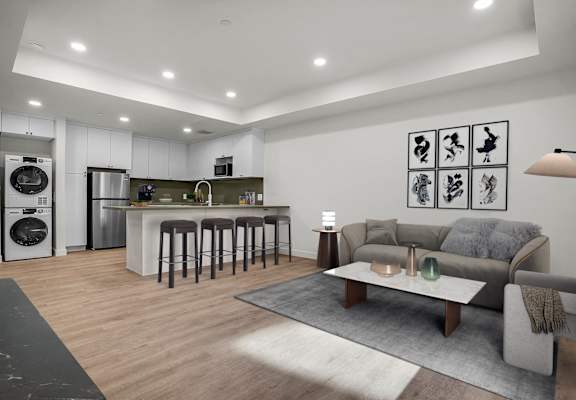 A modern kitchen with a bar area and a living room with a grey sofa.