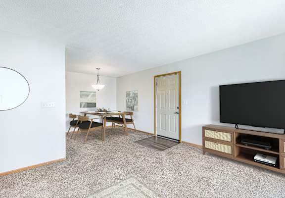 A living room with a television, a dining table, and chairs.