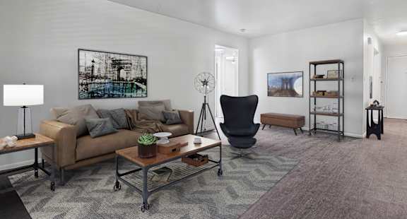 A living room with a brown couch, a black chair, and a grey rug.