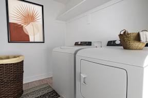 a washer and dryer in a laundry room with a basket and a painting