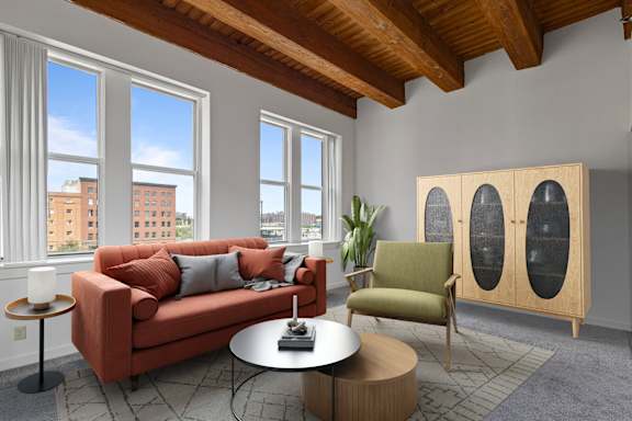 A living room with a red couch, a green chair, and a wooden cabinet.