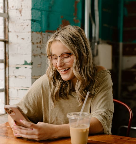 a woman sitting at a table looking at her cell phone