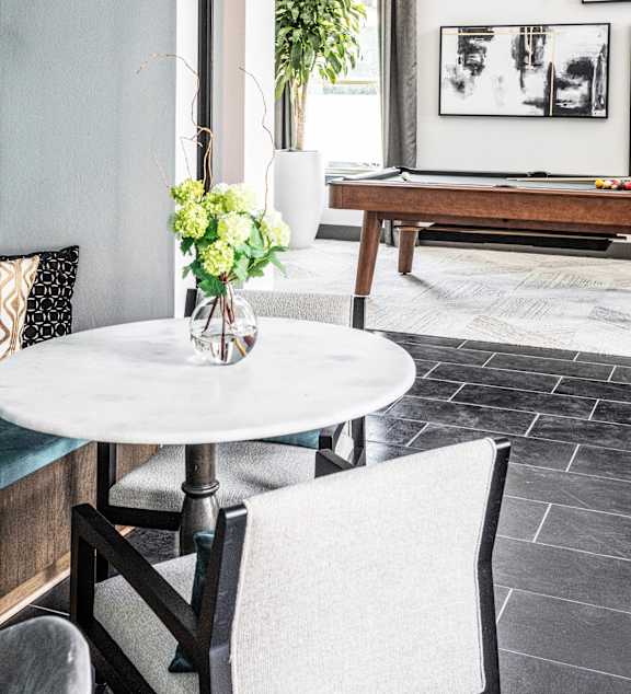 A white table with a vase of flowers on it and a chair in front of it.
