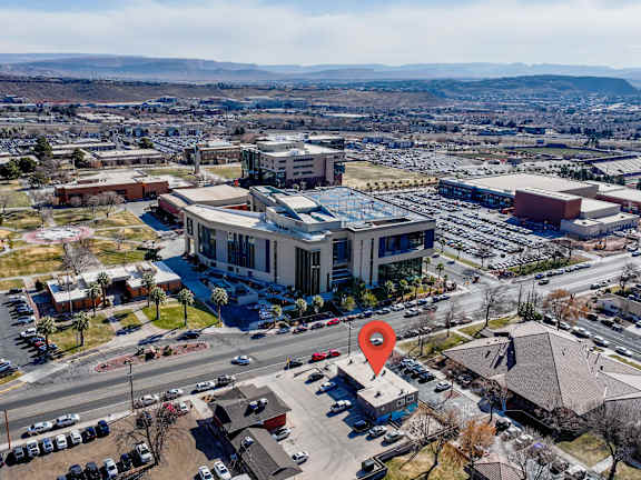 An aerial view of a parking lot with a red pin on a building.